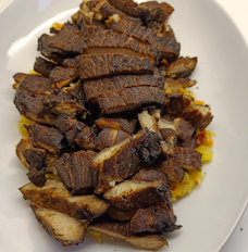 Dish with sliced fried pork on top of a layer of atjar